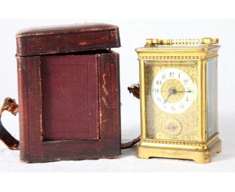 A carriage clock in brass case with floral embossed gilt metal face, subsidiary alarm dial, porcelain chapter ring, 6" high, 