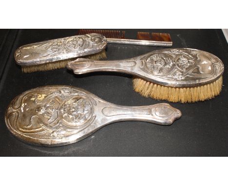 An Art Nouveau embossed silver backed toilet set of two brushes, a mirror and a comb