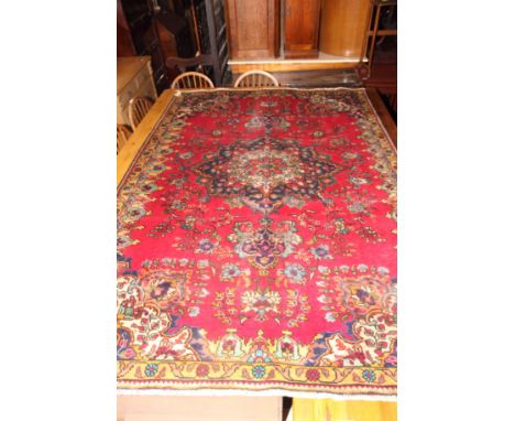A Persian Tabriz rug decorated central floral medallion on a red ground, 94" x 65" approx