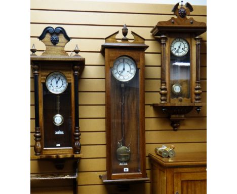 THREE GERMAN VIENNA-STYLE WALL CLOCKS, all with roman two part white enamel dials, one with parcel ebonised case, 92cms, 99cm