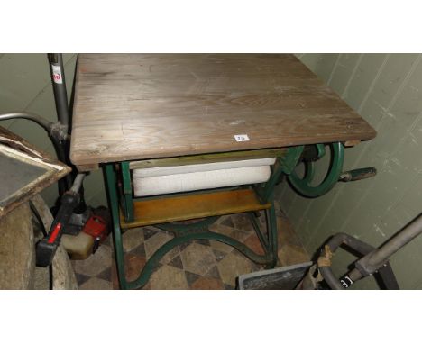 A vintage Ewbank rubber wringer with green painted cast iron frame beneath a rectangular stripped pine folding top