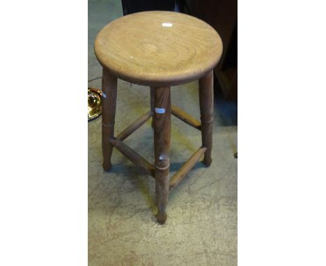 A vintage elm kitchen/work stool with circular seat raised on four splayed turned tapered legs united by stretchers, together