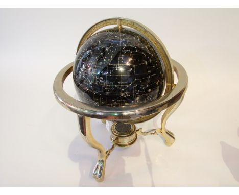 A celestial globe mapping the constellations, the black ground detailed with semi-precious stone inlay raised on a tripod fra