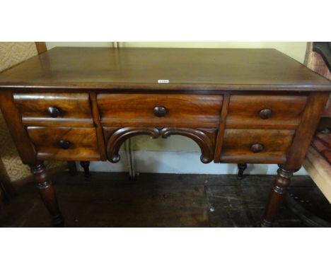 A Victorian mahogany side/writing table fitted with an arrangement of five cushion moulded drawers over a central arch raised