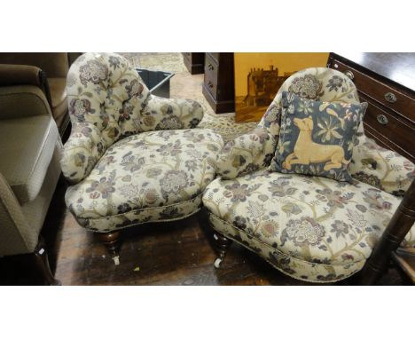 A pair of low Victorian corner/conversation chairs with upholstered finish, the seat with serpentine outline beneath arched b