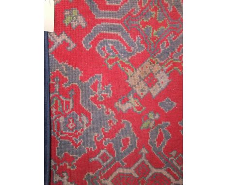 A heavy wool work carpet, the red field interspersed with geometric medallion in shades of blue and green, set within trailin