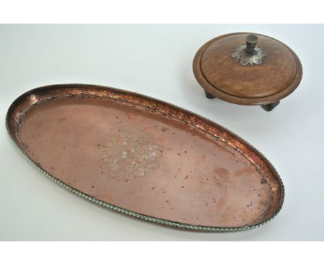 A small beaten copper dish of oval form with applied twisted white metal border and simplistic incised foliate detail to cent