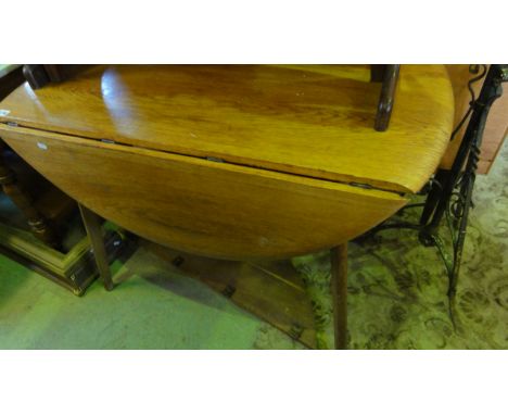 An Ercol style oval drop leaf kitchen table raised on four splayed tapered and moulded legs 