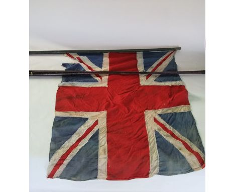 A vintage Union Jack flag suspended on a rustic stained timber pole together with a two sectional split cane fishing rod stam
