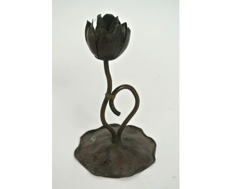 A Japanese bronzed metalwork candlestick, the bowl in the form of an opening waterlily, the stem raised on a single lily pad 