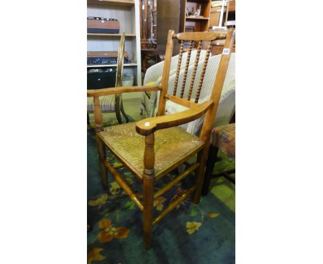 A 19th century countrymade fruit wood open elbow chair with bobbin railed back over a rush seat, raised on simple turned tape