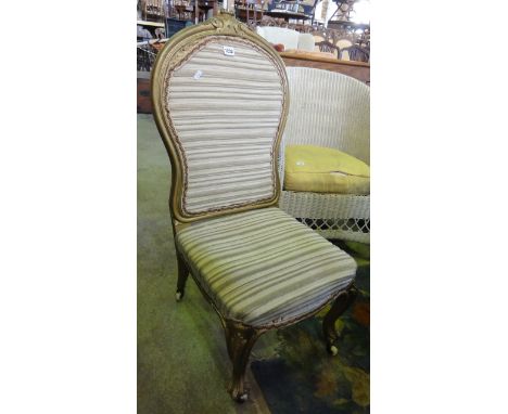 A Victorian nursing chair with upholstered seat and padded shield shaped back within a gilded wood shaped and moulded frame, 