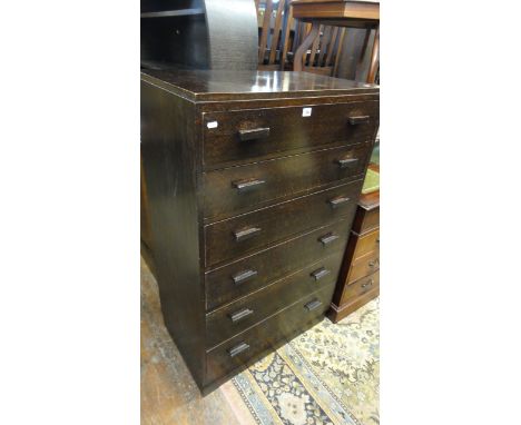 A dark stained oak caddy top bedroom chest of six long graduated drawers with rectangular moulded handles, raised on a slight