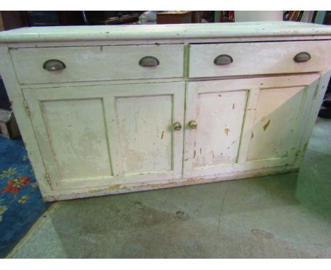 A vintage painted pine kitchen dresser base enclosed by a pair of twin rectangular panelled doors beneath two frieze drawers 