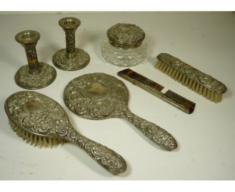 A silver dressing table set comprising a pair of floral embossed dwarf candlesticks and a matching circular glass jar with si