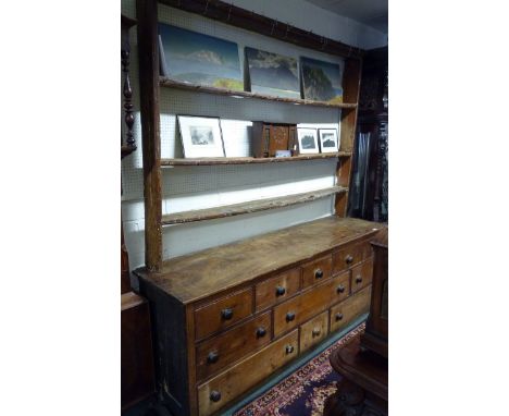 A very large, pine Victorian dresser.  The base with elm top, and fitted with an array of drawers with bun handles, associate