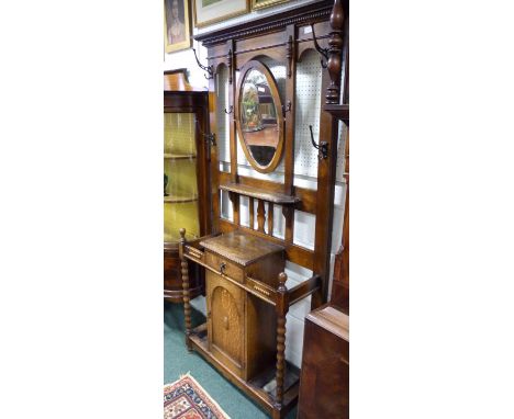 An oak 1930's hall stand.  The base fitted central cupboard, interior shelf, small drawer above, umbrella stand to either sid