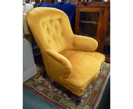 A late Victorian balloon back, button upholstered armchair, on short baluster legs and with ceramic castors. 66cm width x 70c