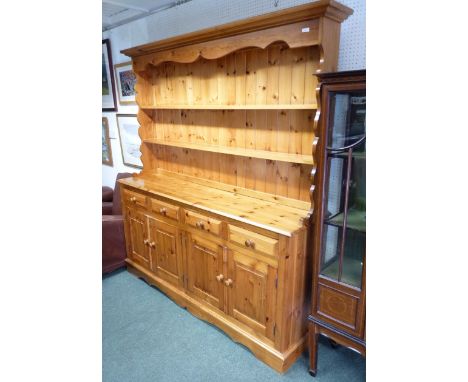 A modern pine kitchen dresser.  The base fitted four panelled doors, enclosing fitted shelf, four narrow drawers above, plank