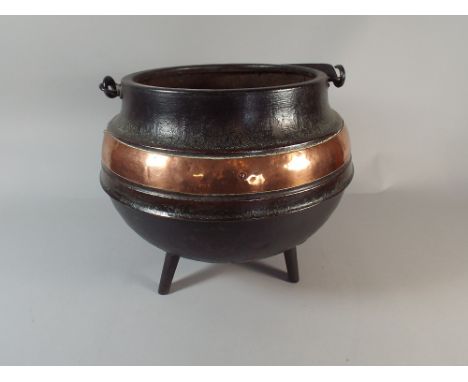 A Metal Coal Bucket with Copper Band on Tripod Feet