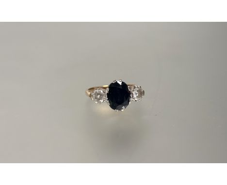 Property of a Lady of Title: a sapphire and diamond three-stone ring, the central oval-cut sapphire claw-set between a pair o