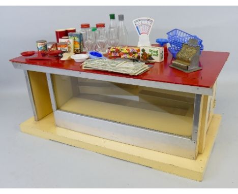 A 1960's cream and red painted wooden play shop, of oblong form with metal framed glass front and two hinged doors to the bac