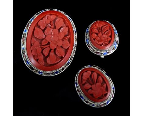 A Chinese Silver filigree and cinnabar lacquer oval brooch, the lacquer carved with a flowering peony branch, in rope twist a