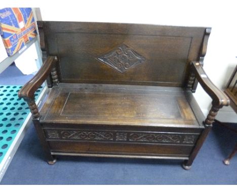 A CARVED OAK MONKS BENCH, with bobbin turned arm supports, approximate size width 117cm x depth 53cm x height 90cm