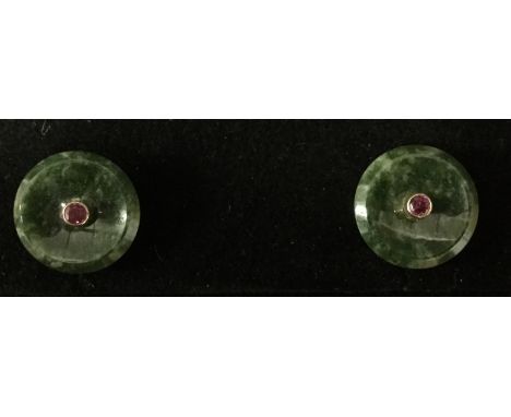 A pair of jade and ruby earrings, circular dished jade platforms central mounted with a single pink ruby, yellow metal fittin