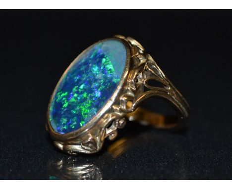 A black opal doublet ring, large oval black opal, flashing green, blue, purple colour play, rollover surround, cast and pierc