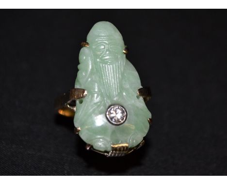 A Chinese Jade and diamond carved panel ring, main jade panel carved as a Bearded Elder Sage, carrying a walking stick, centr