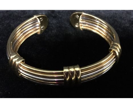 An Italian 18ct gold three colour bangle, seven individual yellow and white gold rods arranged as an arched slave bangle boun
