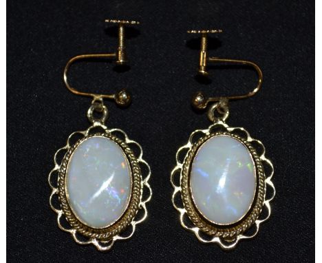 A pair of oval opal earrings, each drop earring set with a central oval opal, flashing blue, red,green and orange colour play