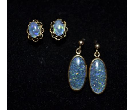 A pair of black opal oval droplet earrings, each flashing, red, amber, blue and green colour play, 9ct gold mounts and pillar