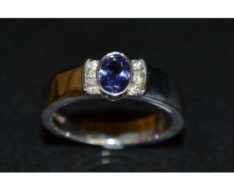 A new tanzanite and diamond ring, central pale blue/purple oval tanzanite, flanked by a row of three diamond accents to each 