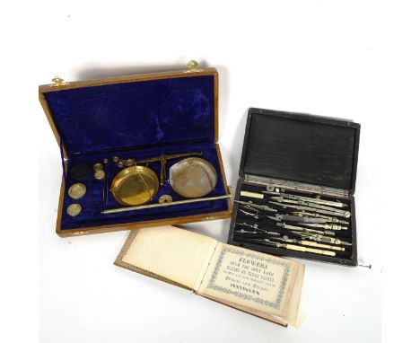 Cased scale with metric weights, drawing instruments, and a dried flower book 