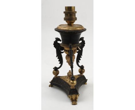 A 19th century lamp base, decorated in black and gilt metal with Classical motifs of griffin's, leaves and flowers, on a trif