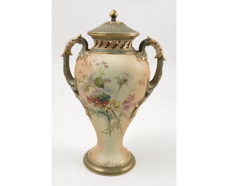 A Royal Worcester blush ivory two handled covered vase, decorated with floral sprays to green and gilt handles and cover, sha