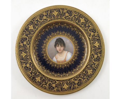 A late 19th/early 20th Viennese plate, decorated with a bust portrait of a young girl, to a blue ground and heavily gilded bo