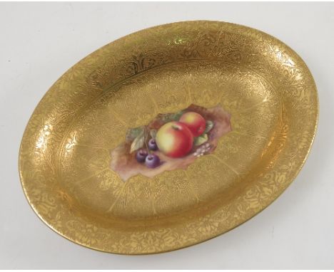 A Royal Worcester oval dish, decorated with a central panel of hand painted fruit by Price, to a deep acid gilt border, diame