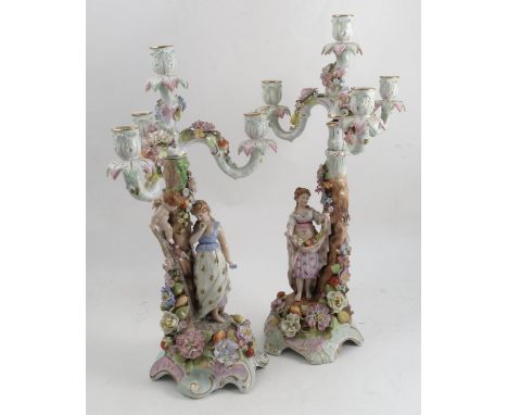 Two similar continental four light candelabra, each decorated with flowers, one decorated with a single figure, the other dec