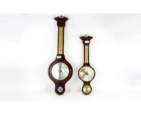 Barometers Two in total, each wall mounted, the first in dark wood with brass tone dial and thermometer. The second in dark w