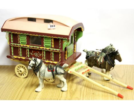A painted wooden gypsy caravan and three ceramic horses.