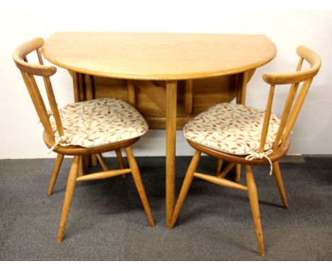 An Ercol drop leaf dining table with two chairs.
