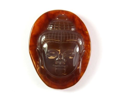 A carved agate amulet of the Buddha head, H. 5.5cm.