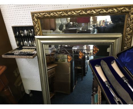 A mirror with orange decoration, a gold framed mirror and two boxes of cutlery.
