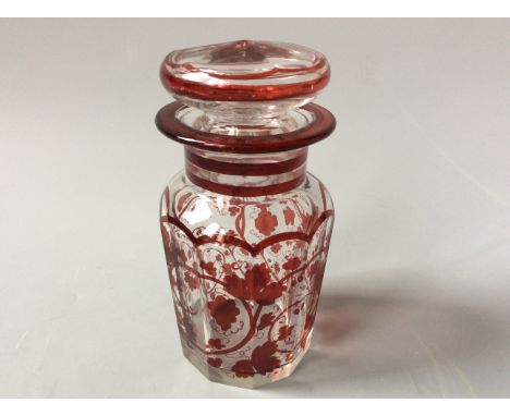 A bohemian glass lidded decanter with red vine detail with an iridescent shell shaped glass vase.