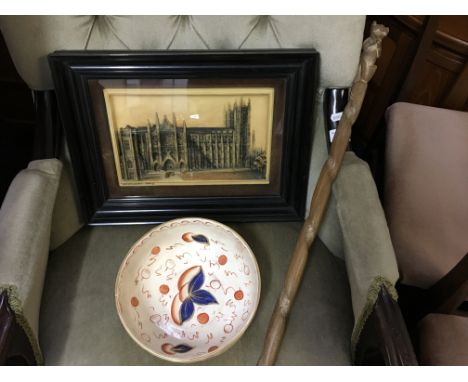 An orange and blue painted fruit bowl, framed plaque depicting Westminster Abbey and wood carved walking stick.