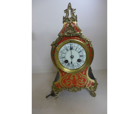 A 19th century French mantle clock of waisted form with lacquered case, circular porcelain dial with Roman numerals adorned w