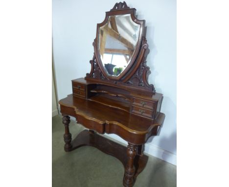 A Victorian mahogany Duchess dressing table with shield shaped bevelled mirror on an elaborately carved supports with four sm